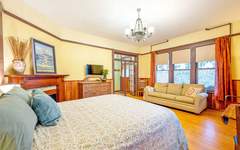 Verandah-Suite-Sleeping-Space-at-Victoria-Falls-House-Nelson-BC Cozy sleeping space with a queen bed and a view of the garden in the Verandah Suite at Victoria Falls House, Nelson BC.