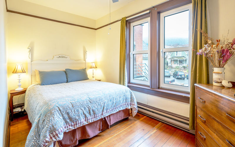 Victoria-Suite-Master-Bedroom-at-Victoria-Falls-House-Nelson-BC Master bedroom with a queen bed in the Victoria Suite at Victoria Falls House, Nelson BC.
